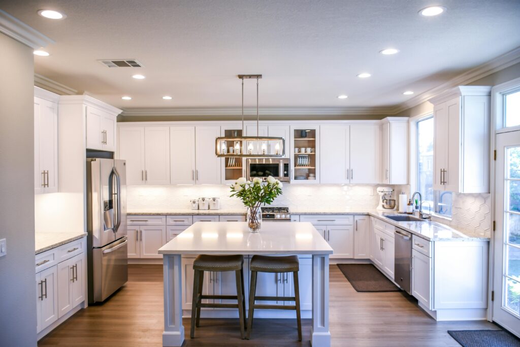 Spacious and elegant kitchen featuring white cabinetry, island, and stainless steel appliances for cooking with flavors.