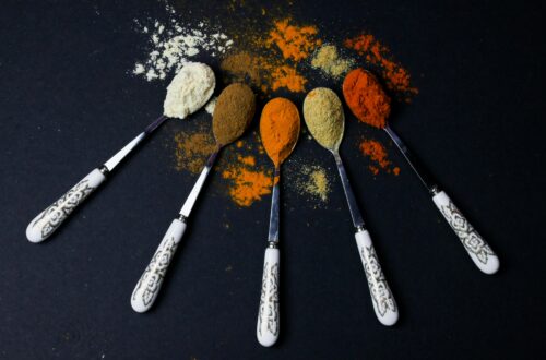 Colorful assortment of flavor in spices displayed on ornate spoons against a dark background, showcasing culinary variety.