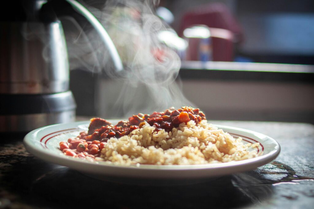 A close-up of steaming Puerto Rican rice with beans, captured in warm afternoon light.