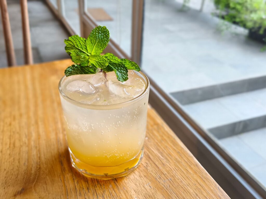 A chilled glass of mint lemonade with ice and fresh mint leaves served on a wooden table.