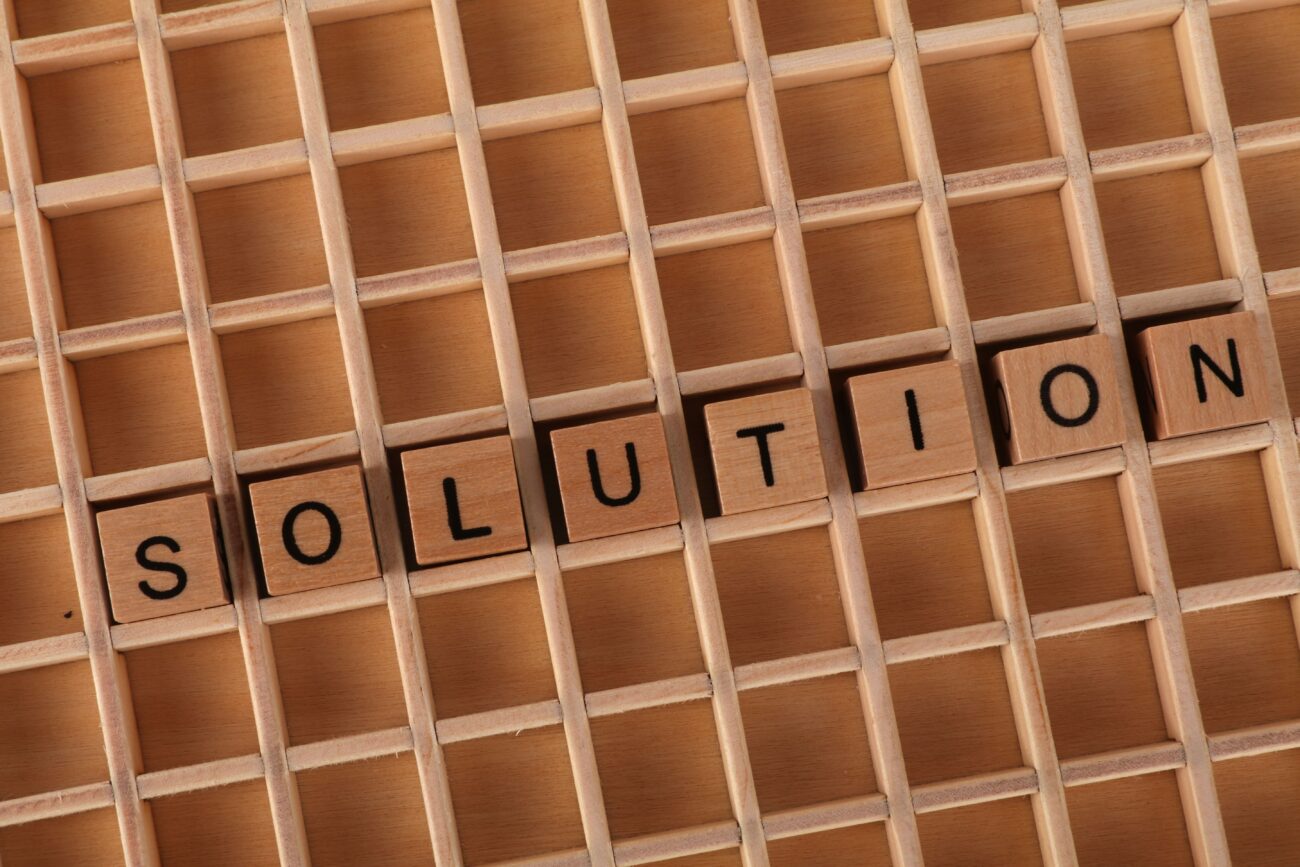 Word tiles spelling 'solution' on a wooden grid background for business concept.