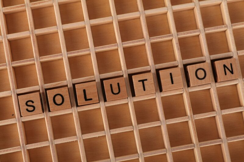 Word tiles spelling 'solution' on a wooden grid background for business concept.