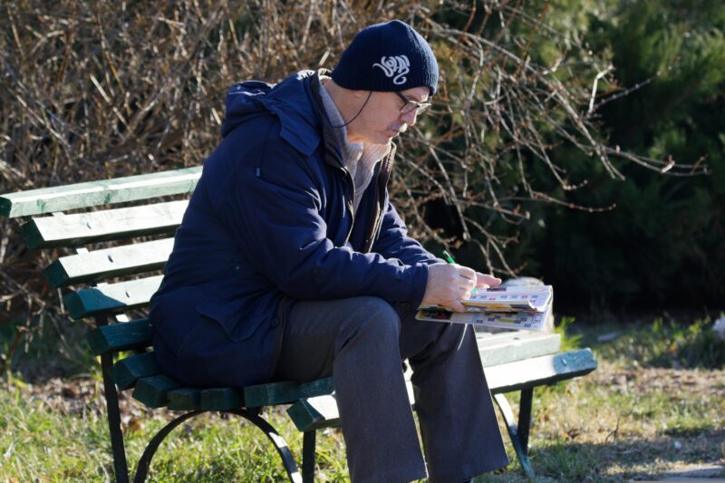 A man focusing on a crossword puzzle for optimal brain health.
