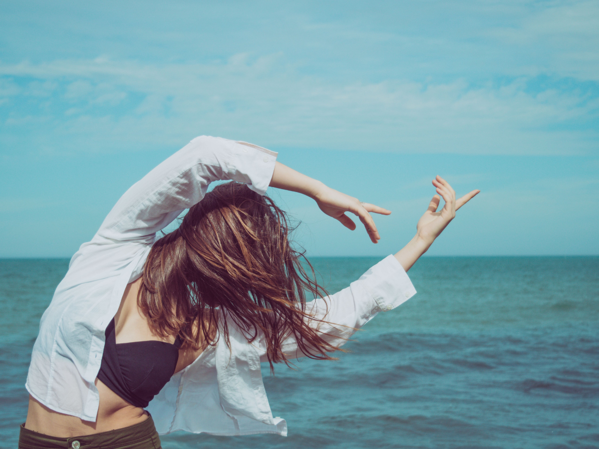 A woman by the water, woman stretching by the ocean, the pisces woman